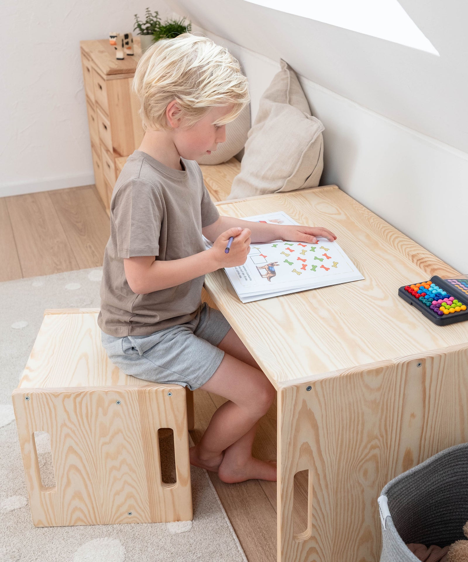 Kind sitzt an dem Wendetisch und malt.