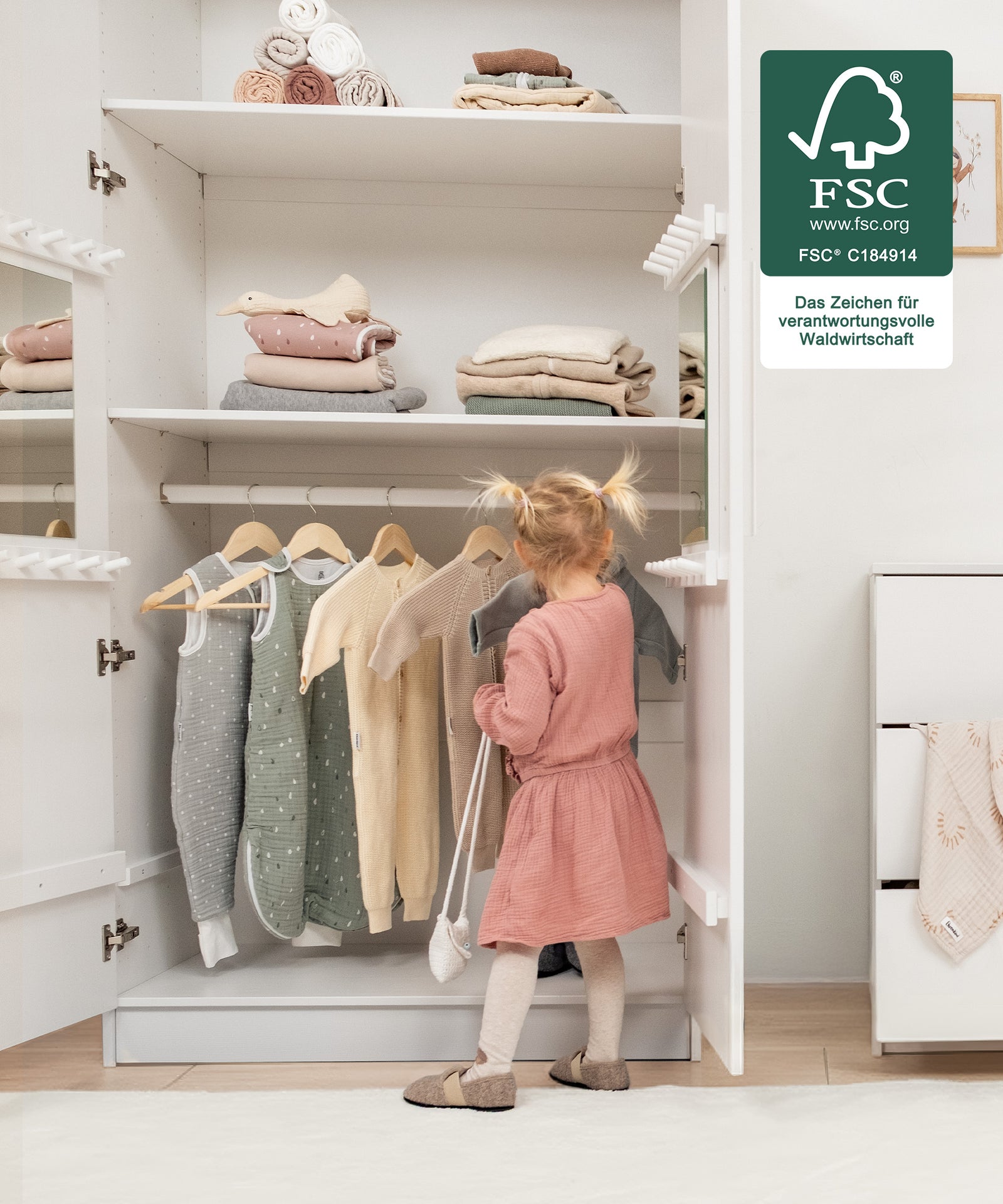 Für kleine Hände gemacht*Die kindgerechte Höhe ermöglicht selbstständiges Anziehen und Aufräumen - unterstützt spielerisch die Entwicklung im Alltag.| Mädchen räumt selbstständig die Kleidung in den Kleiderschrank.