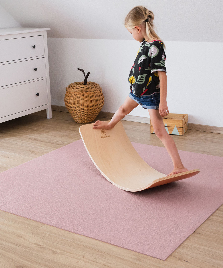 Dämpfend & isolierend*Die Krabbelmatte ist stoßdämpfend, wärmeisolierend und auch für Böden mit Fußbodenheizung geeignet. Krabbelmatte in Rosé.|Kind balanciert mit BalanceBoard auf Krabbelmatte.