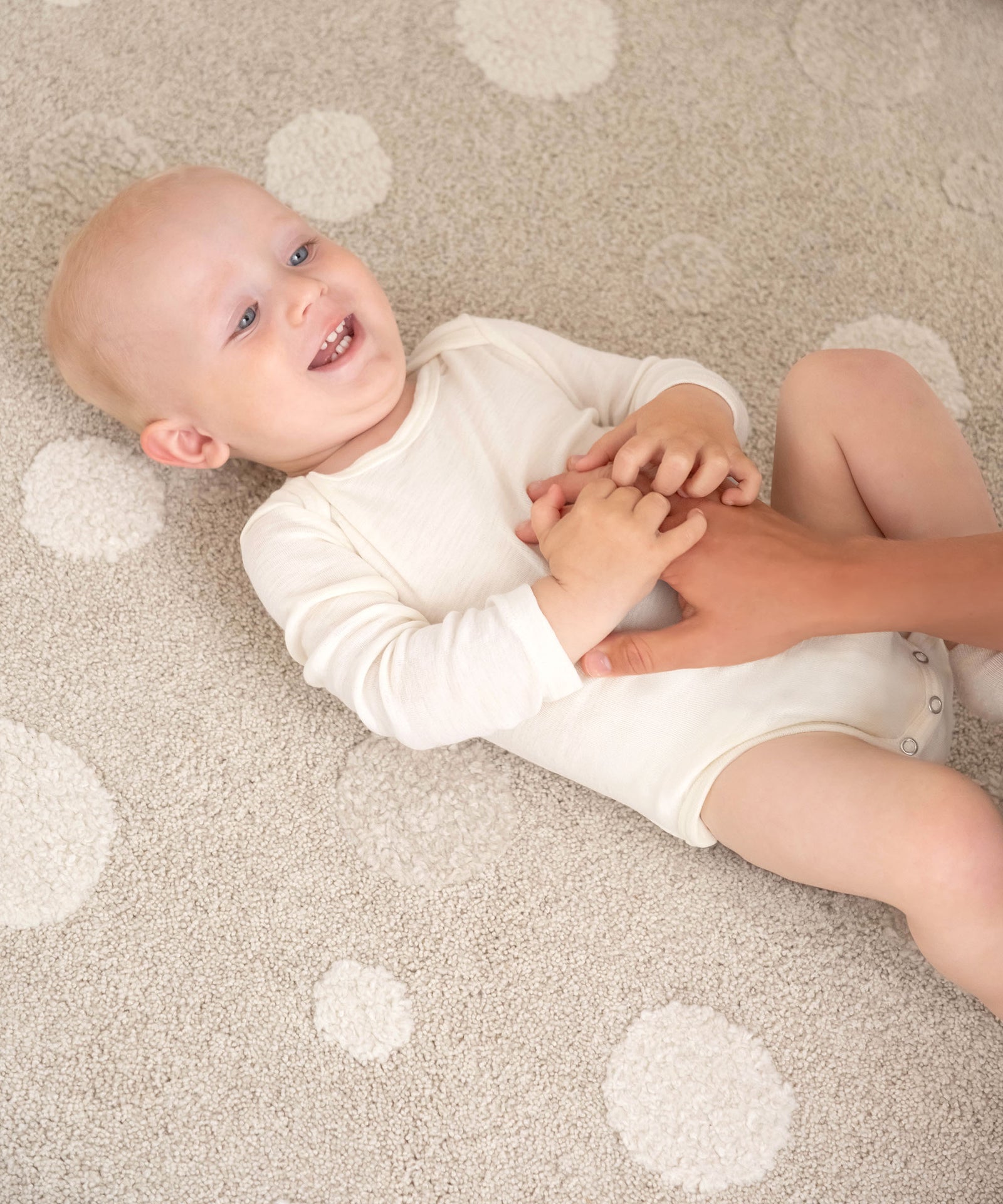 Praktischer Schlupfbody*Durch die Schlupfform und Knöpfung im Schritt einfach anzuziehen. Die Druckknöpfe sind nickelfrei und unbedenklich für Babyhaut.|Baby liegt lachend auf Teppich.