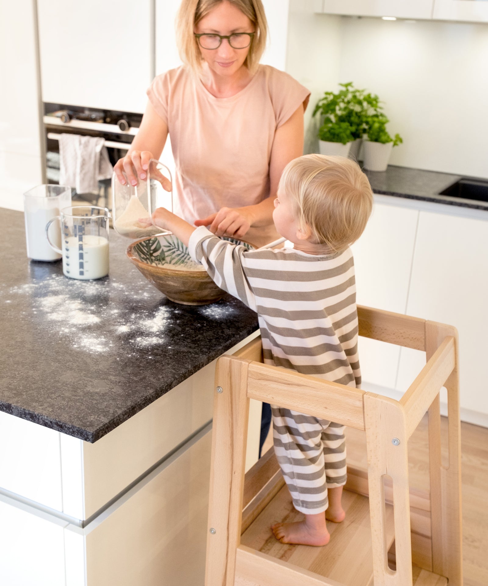 Kind steht im Lernturm beim gemeinsamen Kochen.