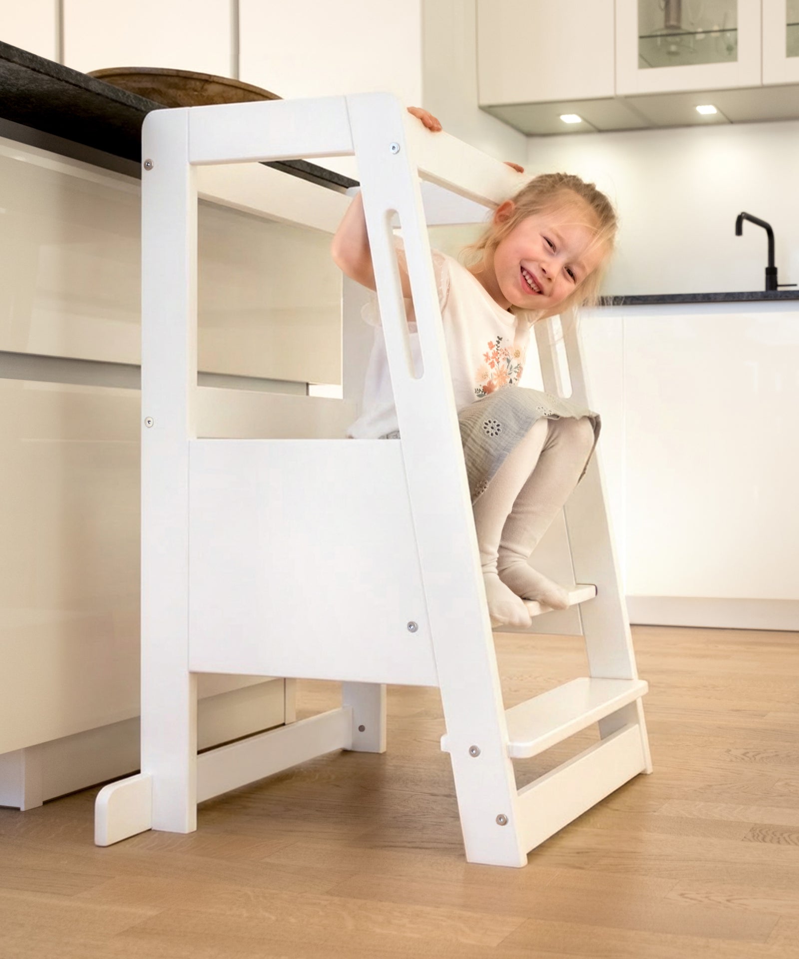 Kind sitzt entspannt auf dem Lernturm aus Buchenholz.