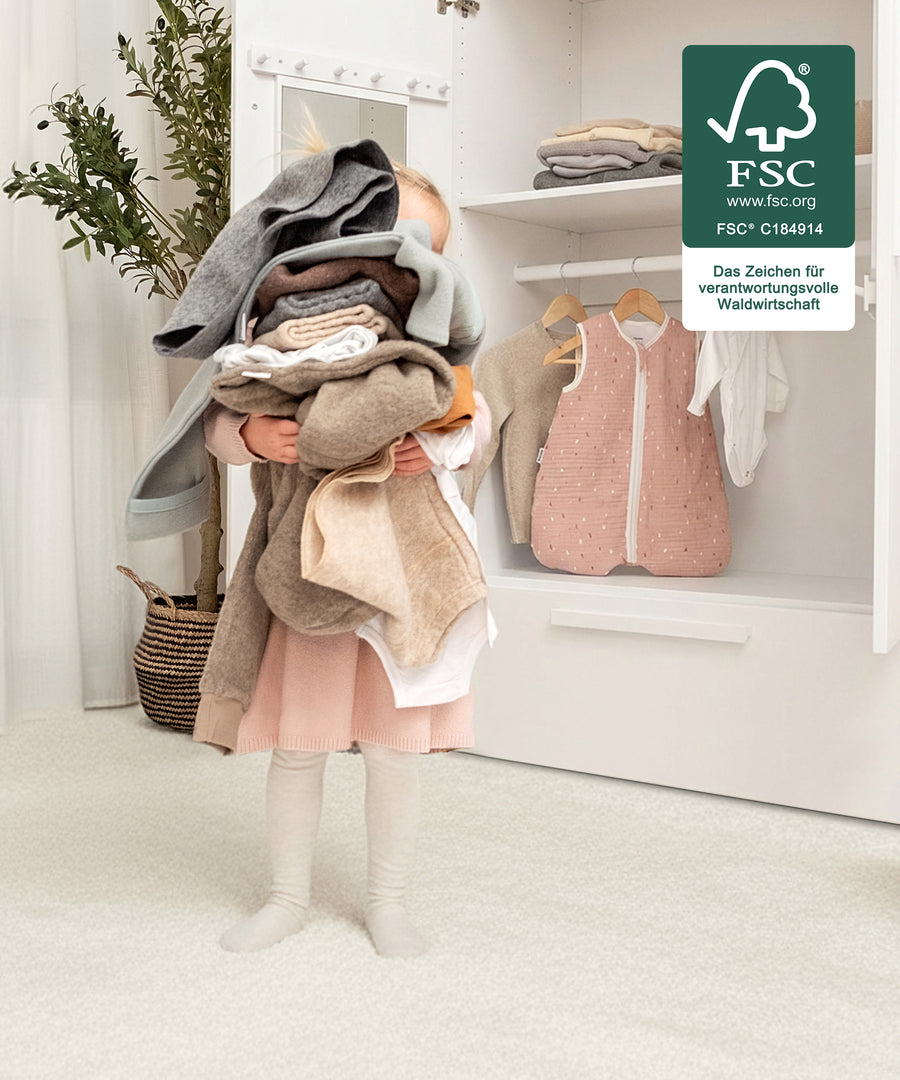 Mädchen trägt selbstständig die Kleidung aus dem Kleiderschrank.