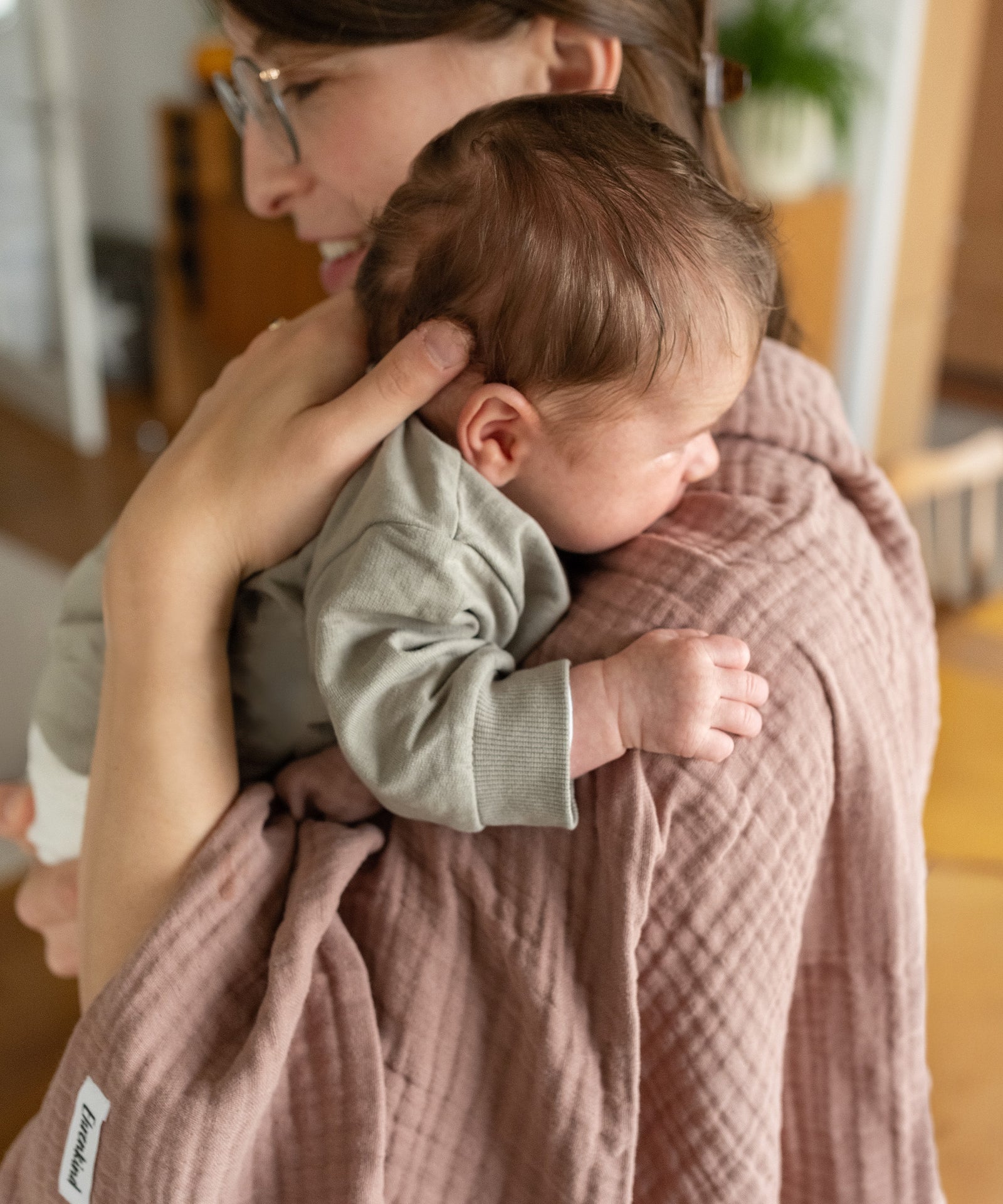 Praktisch & vielseitig*Mit den Tüchern erhältst du ein besonders saugfähiges, kuscheliges & vielseitig einsetzbares Produkt, das den Alltag mit Baby erleichtert.|Mutter mit Baby und Wolltuch in Rose über der Schulter.
