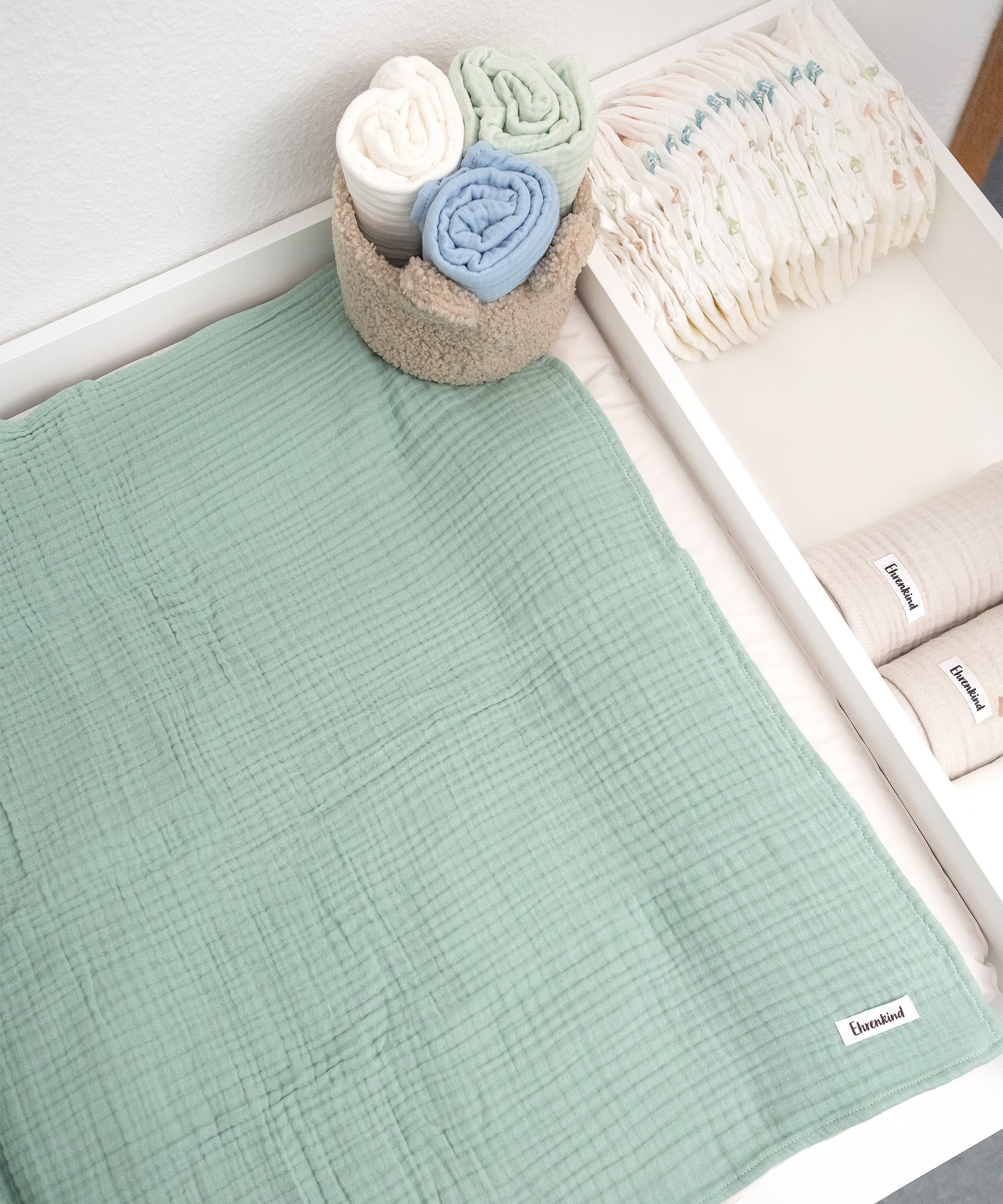 Mulltuch in Jade aus der Farbvariation Blau auf Wickelkommode.