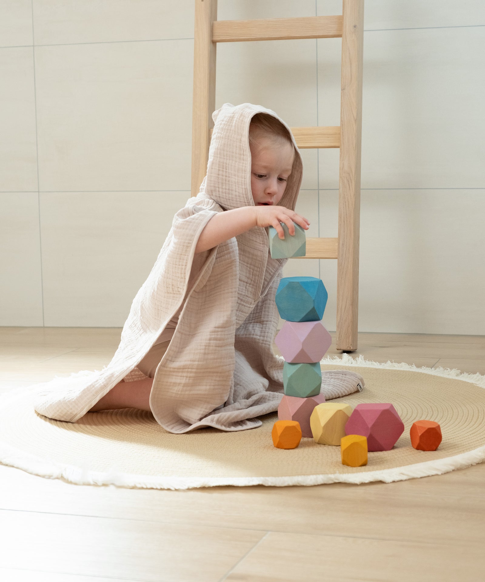 Sanft eingehüllt nach dem Baden*Das 4-lagige Musselin-Gewebe ist weich und saugfähig. Es trocknet dein Kind sanft und fühlt sich angenehm auf der Haut an.|Kind spielt im Musselin Badeponcho.