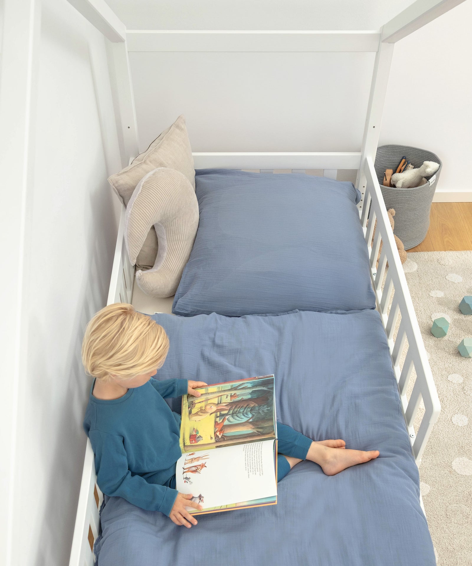 Kind sitzt im Hausbett und liest ein Buch.