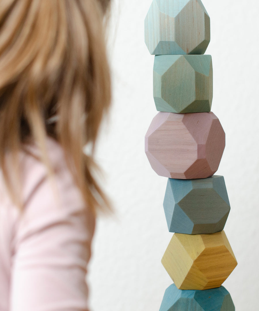 Kind mit Turm aus Stapelsteinen Bunt.