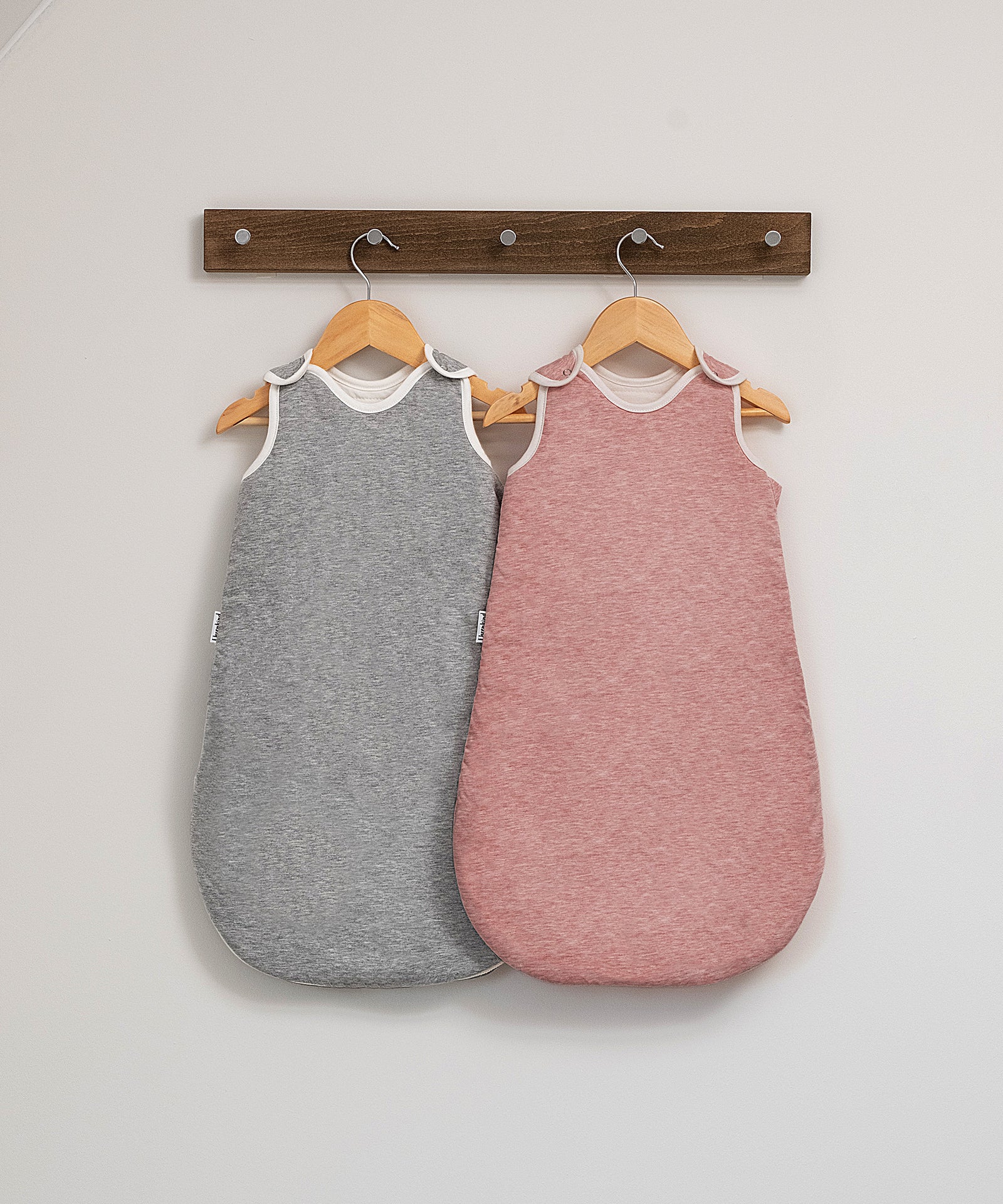 100% natürliche Materialien*Der Schlafsack aus Bio-Baumwolle mit reinster Schurwollfüllung bietet deinem Baby Geborgenheit und ein optimales Schlafklima.| Schlafsack in Rosé und Hellgrau auf dem Bügel.