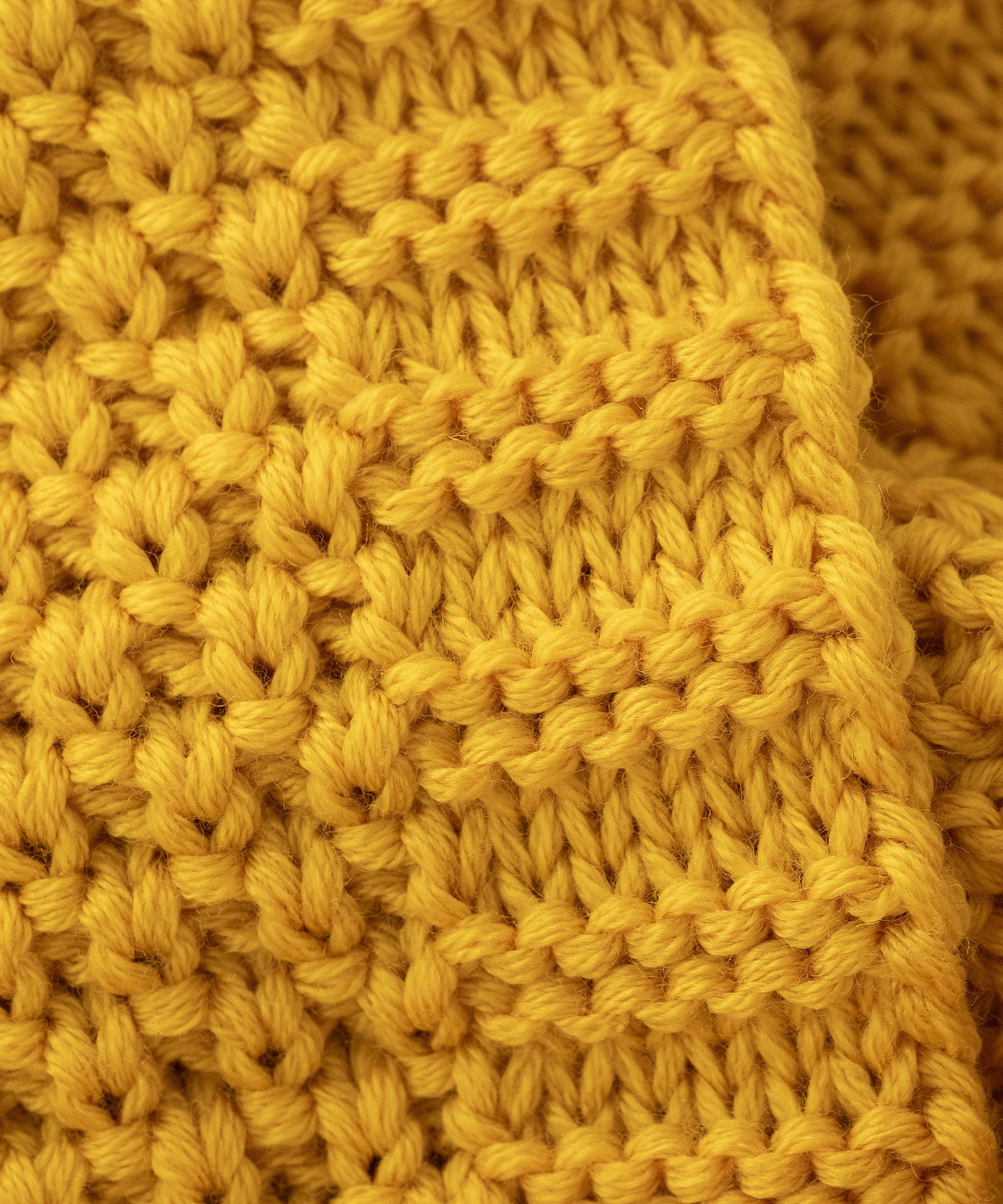 Made in Germany*Hochwertig gefertigt aus Merino Schurwolle und nachhaltig aus kontrolliert biologischer Tierhaltung in Deutschland produziert.| Nahaufnahme von dem Schlauchschal Grobstrick Safran.