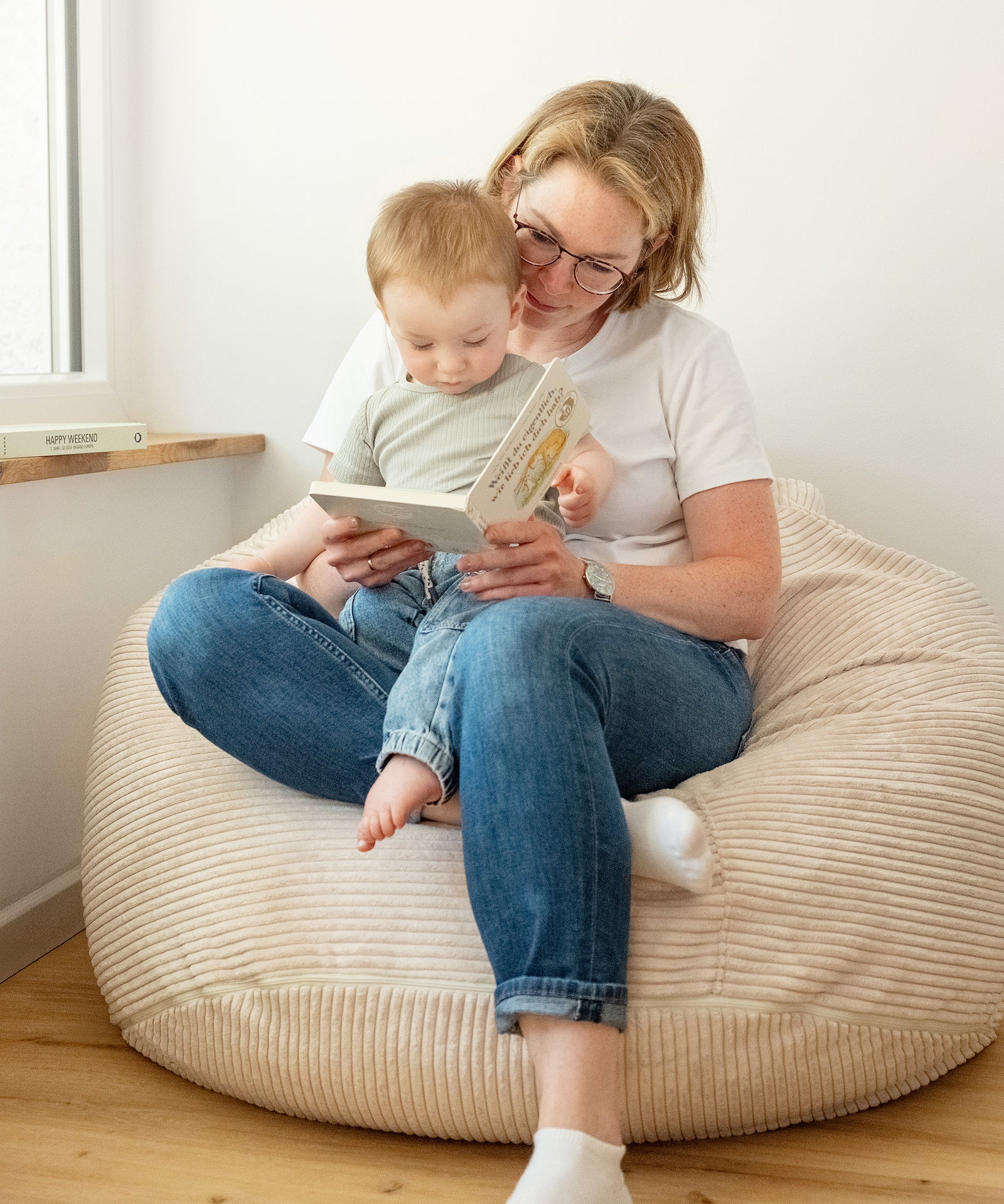 Mama und Baby lesen ein Buch auf dem Sitzsack.