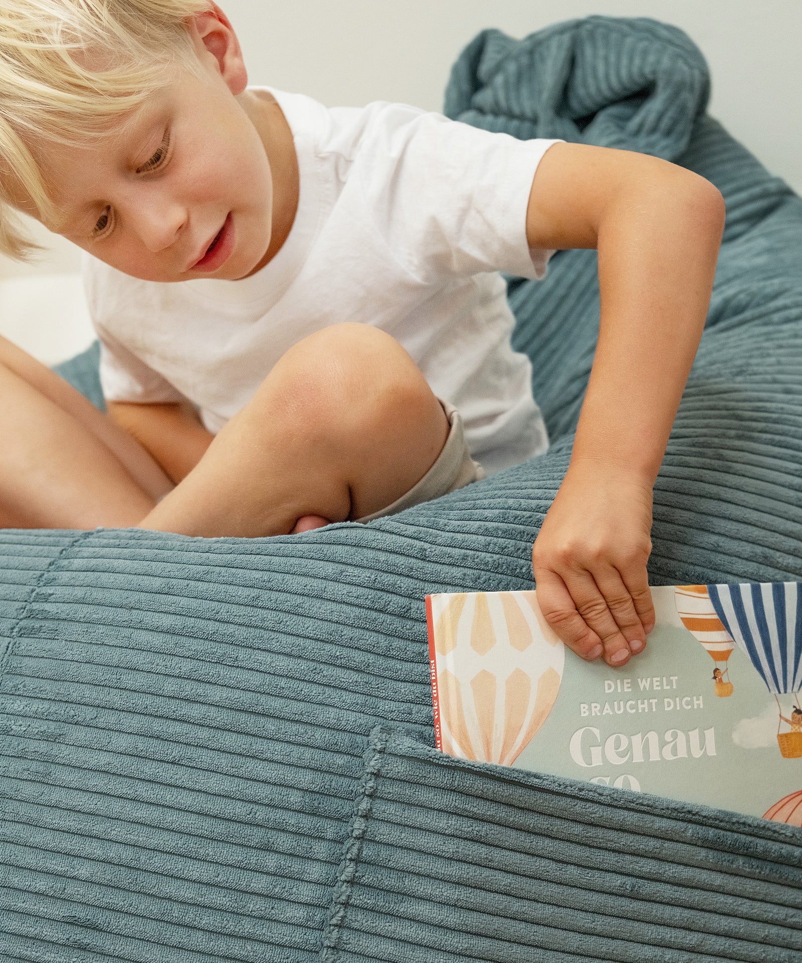 Kind zieht ein Buch aus der Seitentasche des Sitzsacks.