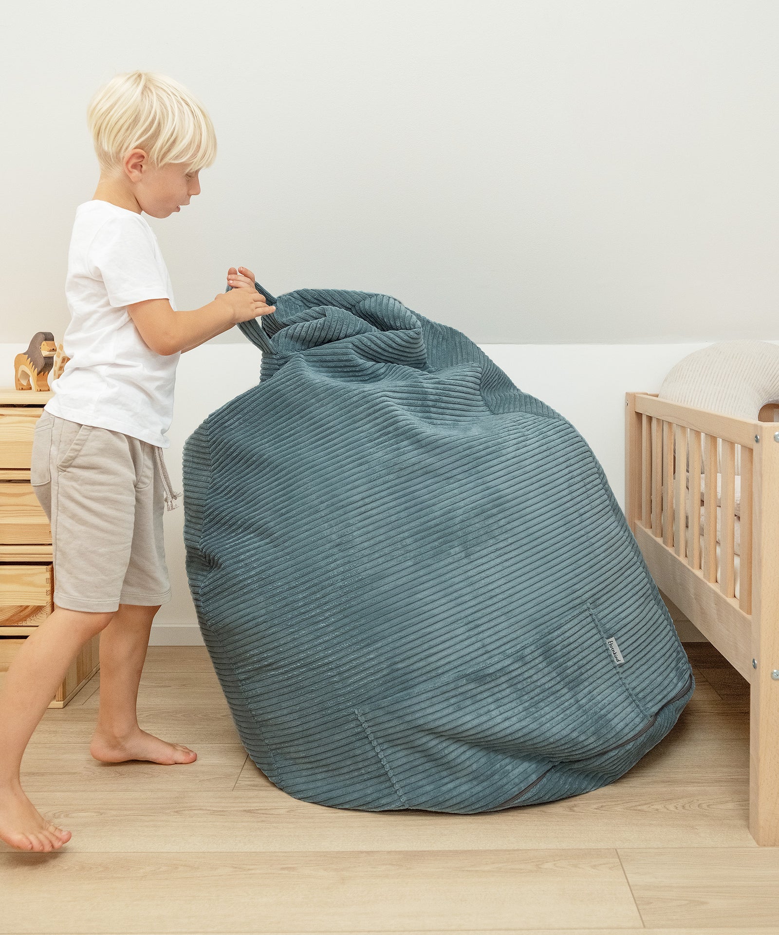 Einfach transportieren*Dank praktischem Griff lässt sich der Sitzsack mühelos von Raum zu Raum tragen – für flexible Nutzung im Alltag.|Kind hält Kinder-Sitzsack am Tragegriff.