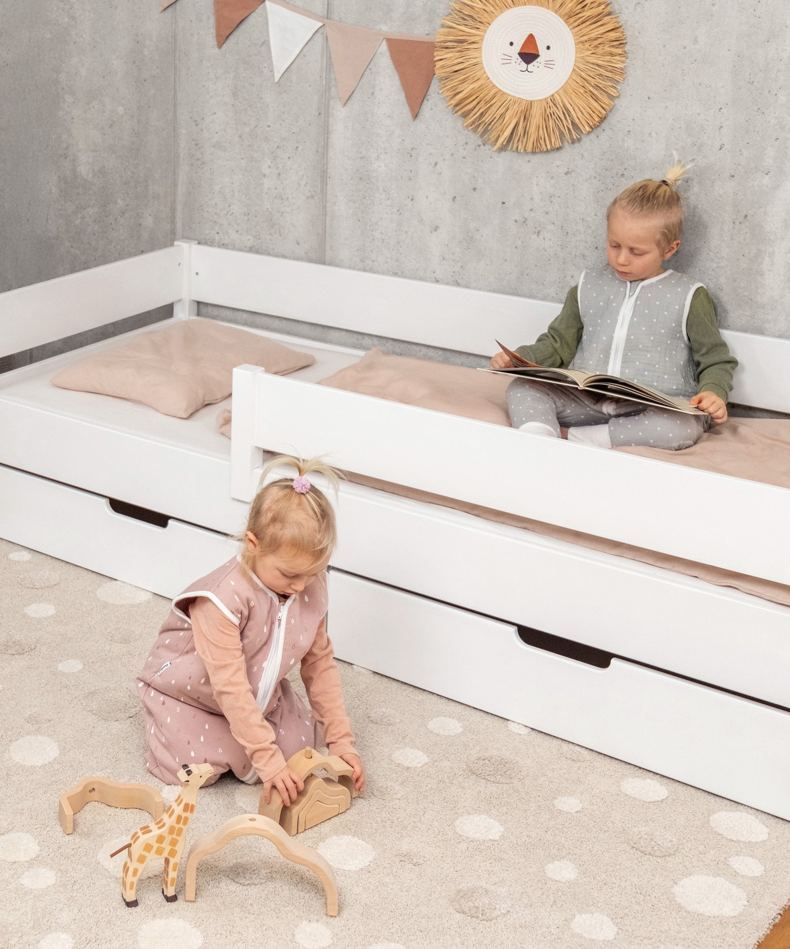 Spielende Kinder am Kinderbett mit Schubladen in Weiß.