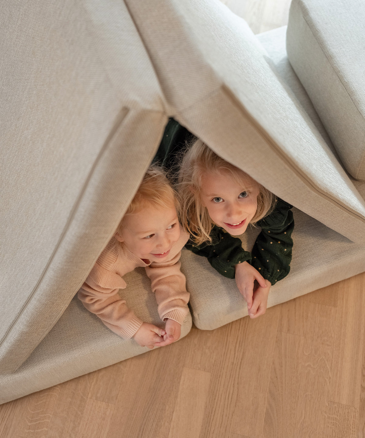 Zwei Mädchen haben aus dem Spielsofa eine Höhle gebaut.