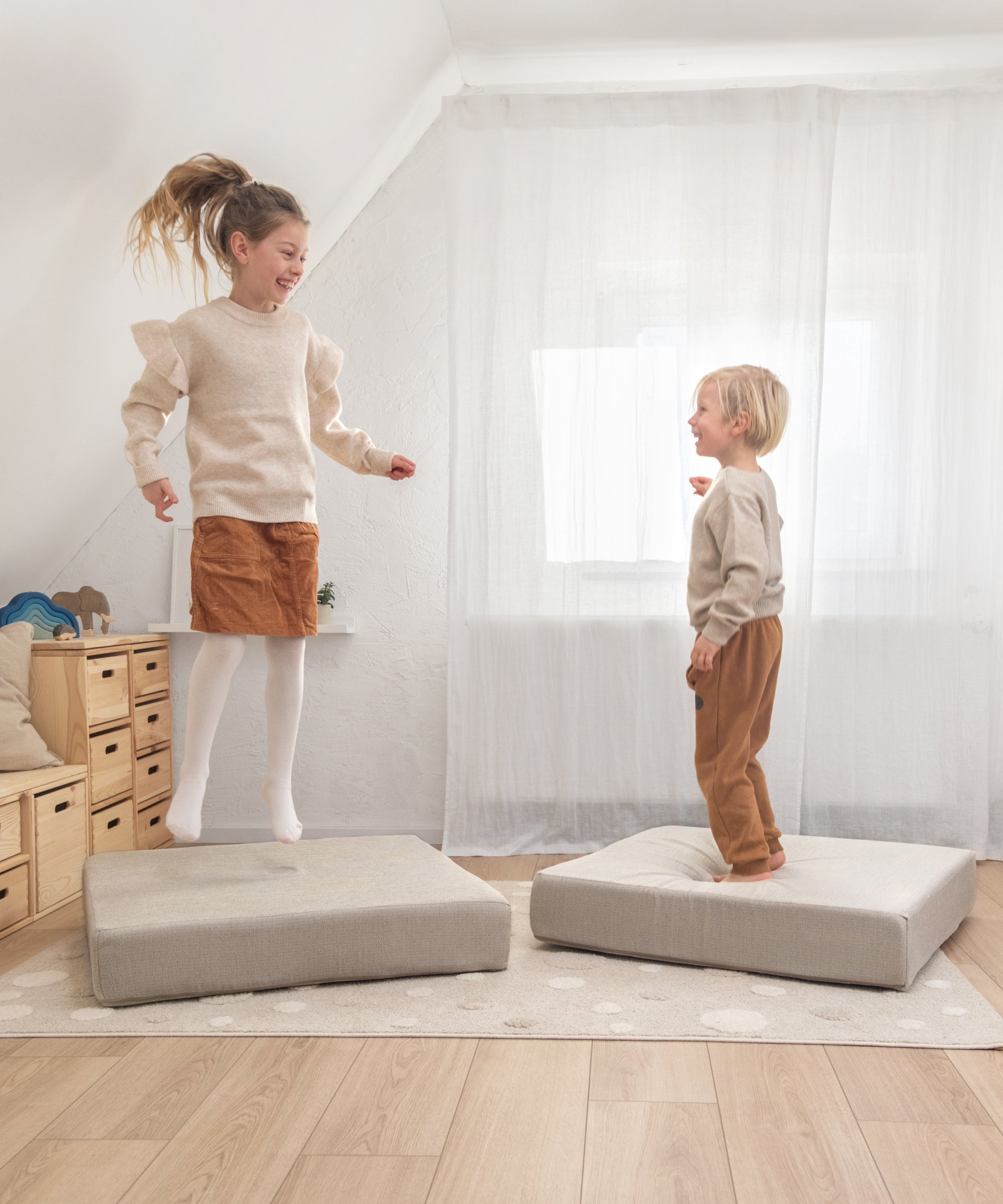 Zwei Kinder spielen auf den Polstern des Spielsofas.
