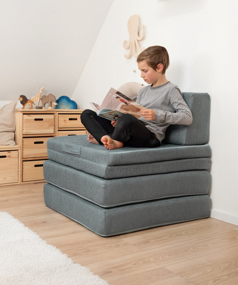 Das Spielsofa kann zu einem erhöhten Stuhl zusammengeklappt werden.