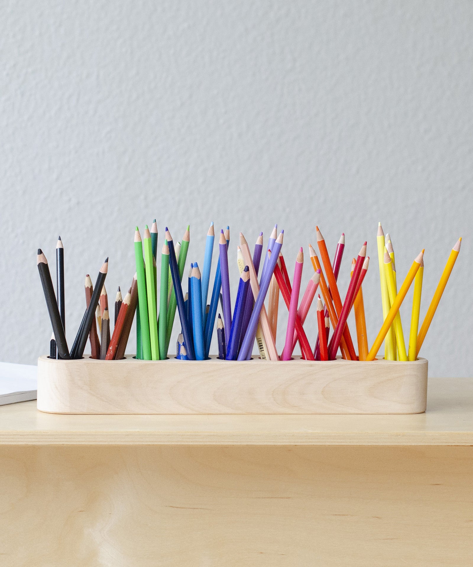 Übersichtlich*Die neun Vertiefungen in verschiedenen Farben bieten Platz für etwa 90 Stifte.|Stiftehalter aus Holz mit Buntstiften befüllt.