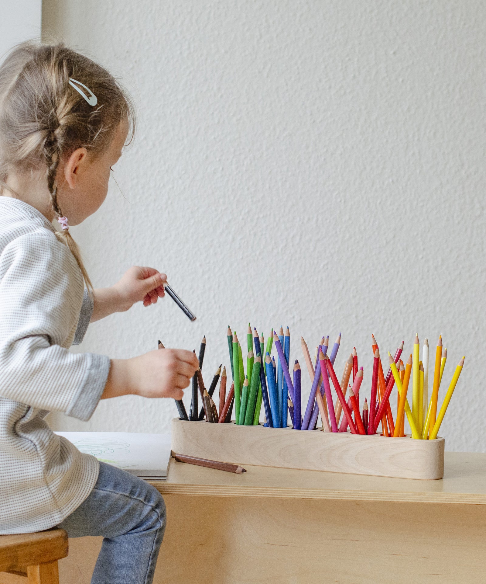 Mädchen räumt nach Malen und Basteln Stift zurück in Stiftehalter.