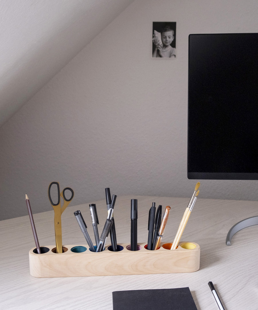 Stiftehalter steht auf Schreibtisch neben Computermonitor.
