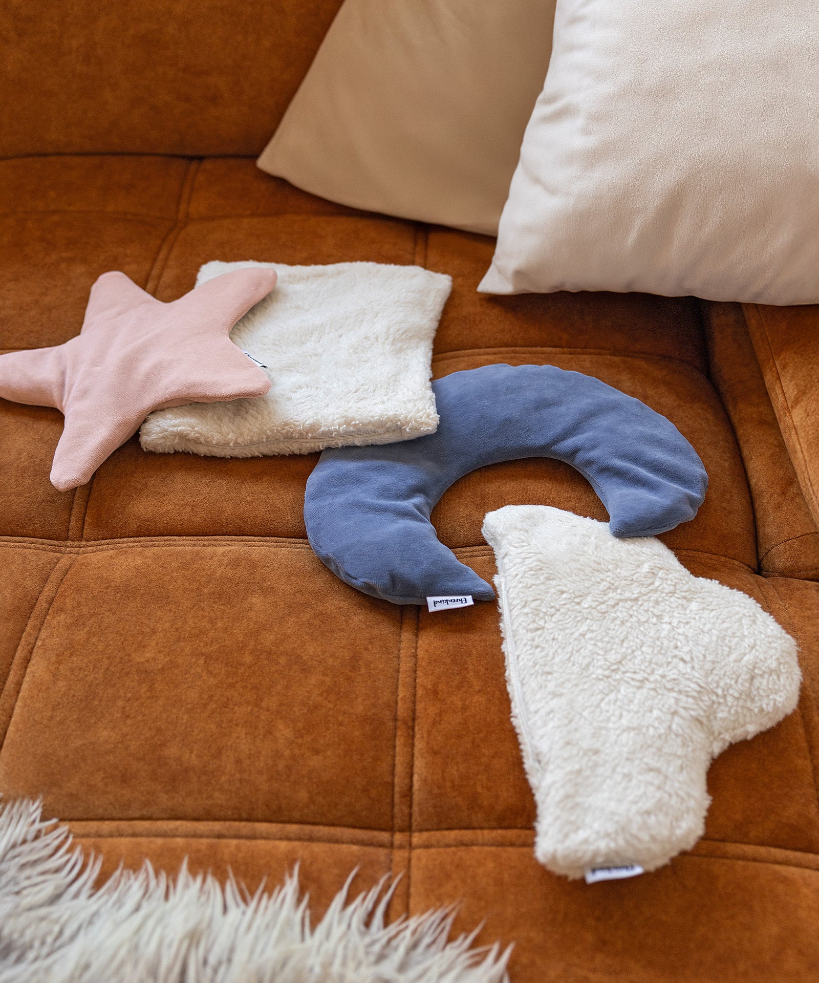 Verschiedene Wärmekissen liegen dekorativ auf einem Sofa.