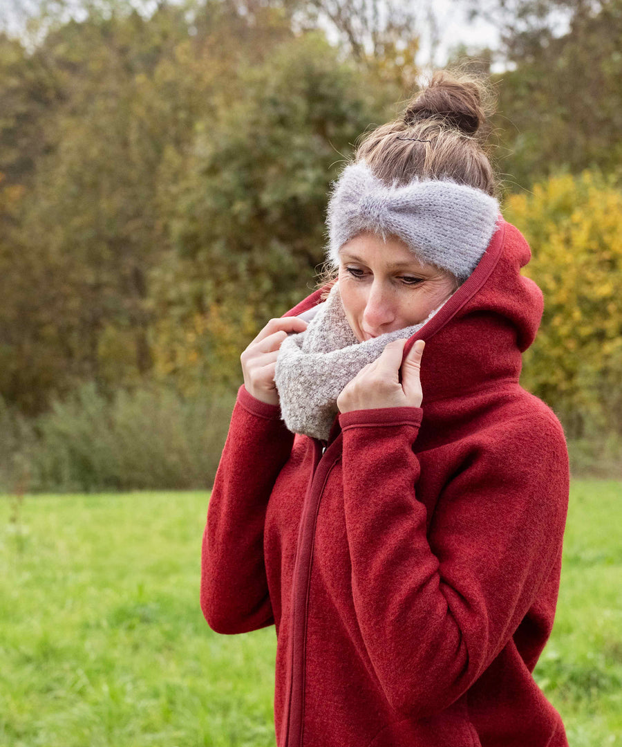 Wärmende Kapuze*Die Kapuze ist mit hautfreundlichem Baumwolljersey gefüttert und schenkt die wohlige Wärme natürlicher Wolle, ganz ohne Kratzen.|Frau mit roter Walkjacke Damen zieht Kapuze auf.