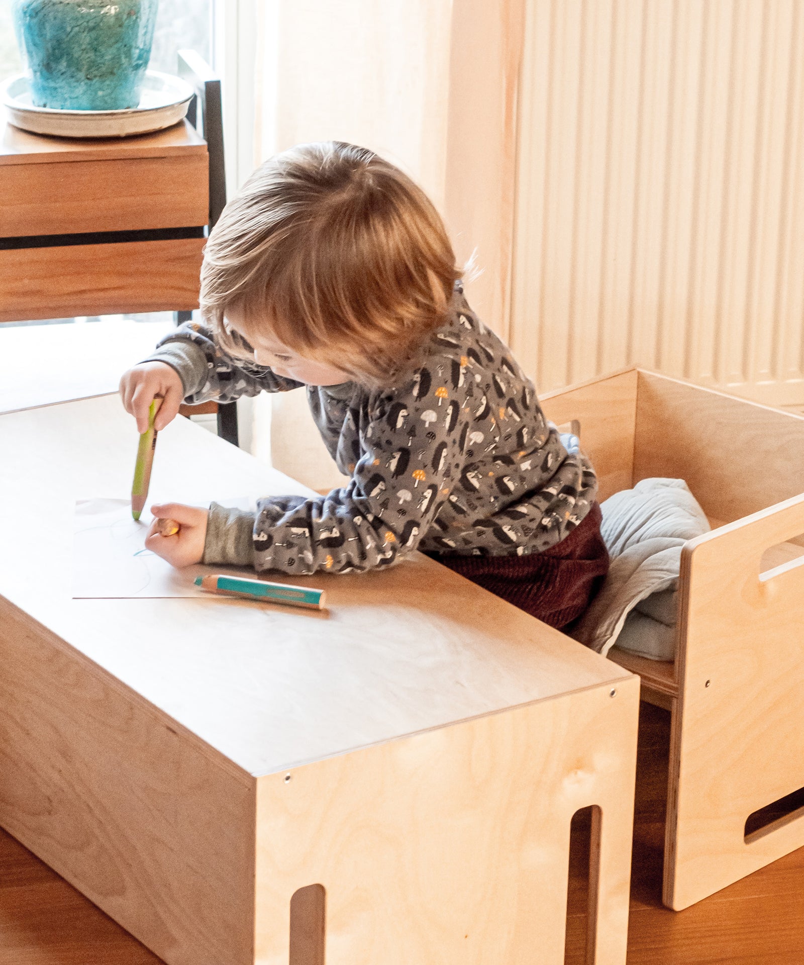 Fördert die Motorik*Durch die unterschiedlichen Höhen kann dein Kind sich mit den Füßen auf dem Boden abstützen und gewinnt ein Gefühl fürs Stehen.| Kind sitzt auf dem Hocker und malt auf der Wendebank.