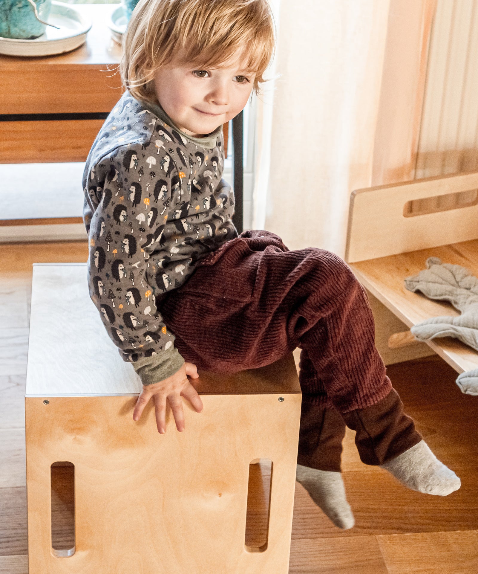 Praktische Wendemöbel*Als Bank, Hocker oder Tisch: Unsere Wendemöbel sind die idealen, mitwachsenden Spielmöbel - egal, wie du sie drehst und wendest!| Kind sitzt auf dem Wendehocker.