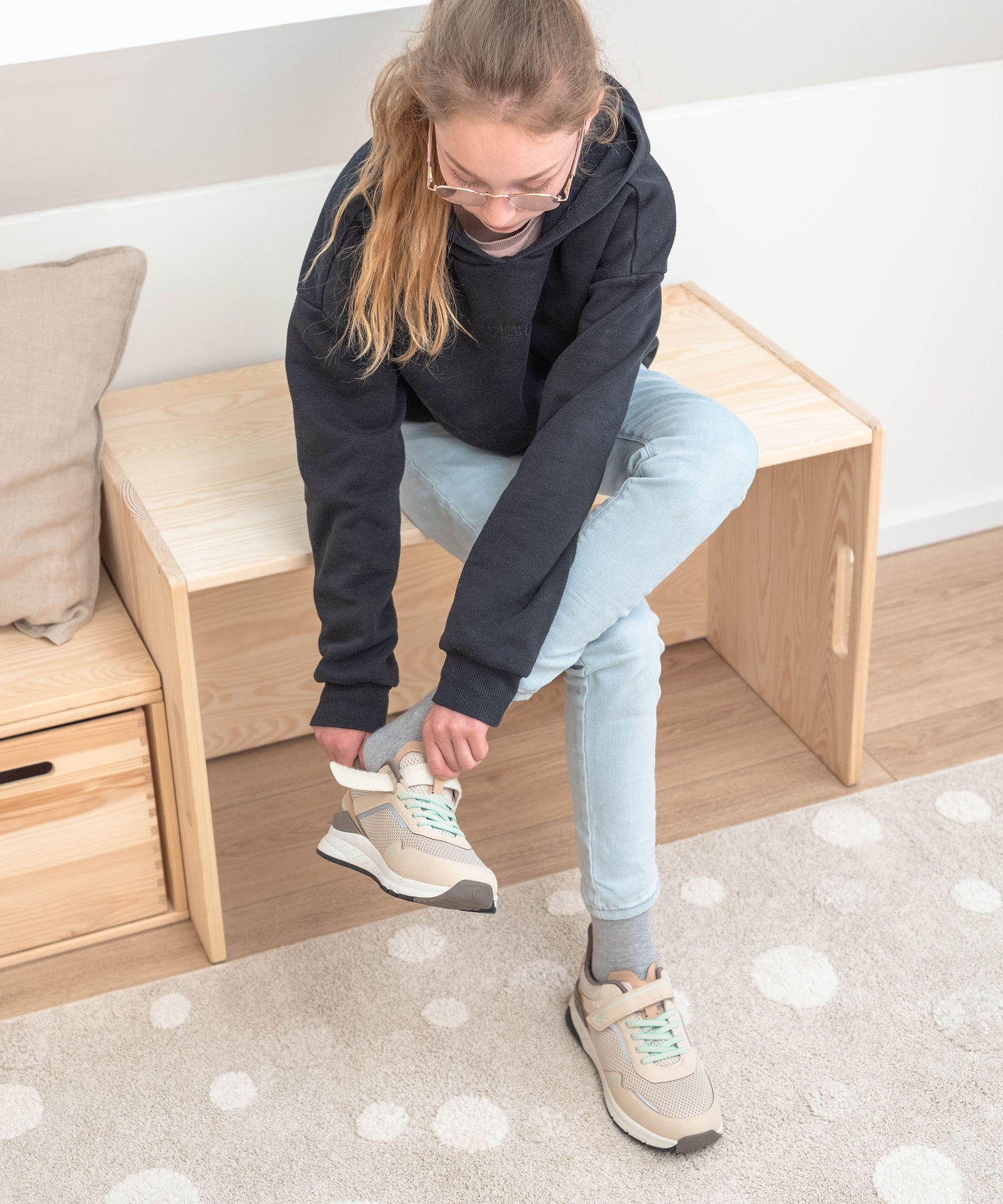 Kind sitzt auf dem umgedrehten Wendetisch und nutzt ihn als Bank um sich die Schuhe anzuziehen.