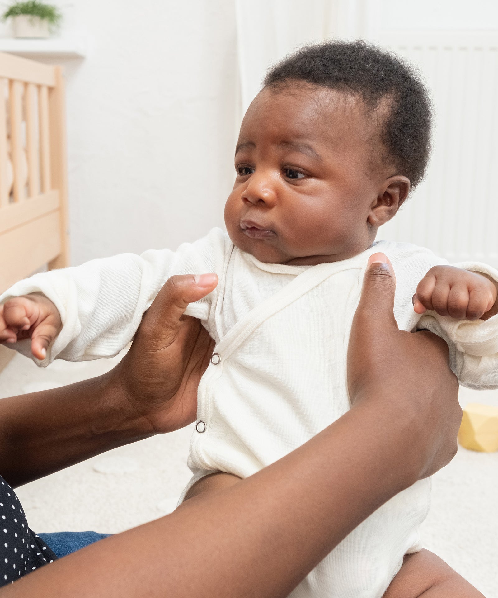 Selbstreinigende Wirkung*Wolle nimmt kaum Gerüche auf - Bakterien haften schlecht an, Gerüche werden reduziert. Daher ist kein häufiges Waschen nötig.|Baby wird von Mama gehalten.