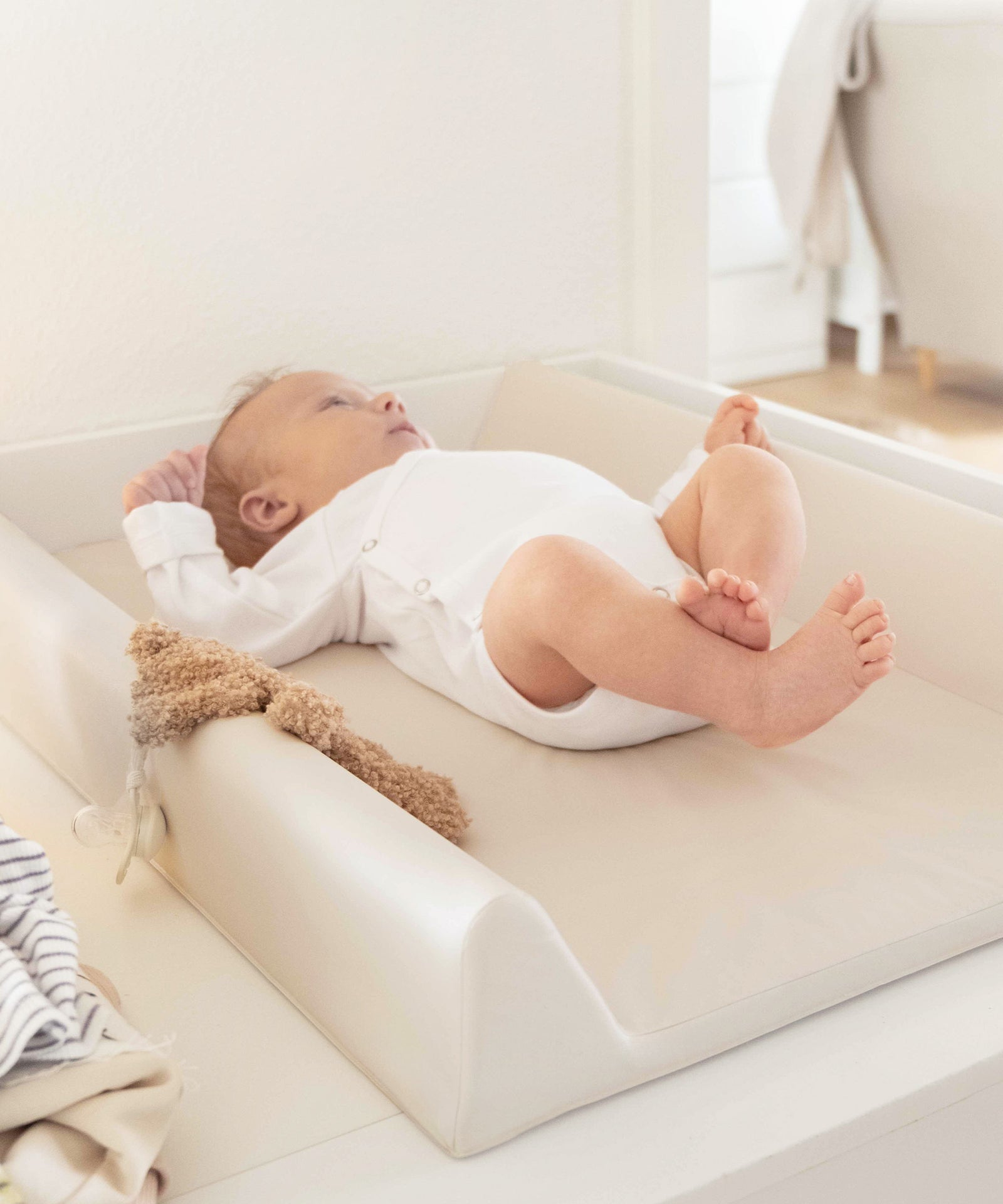 Weich gepolstert*Auf der weich gepolsterten Wickelauflage liegt dein Baby bequem - für Momente voller Nähe und Fürsorge.|Baby liegt auf abwaschbarer Wickelauflage in Beige.