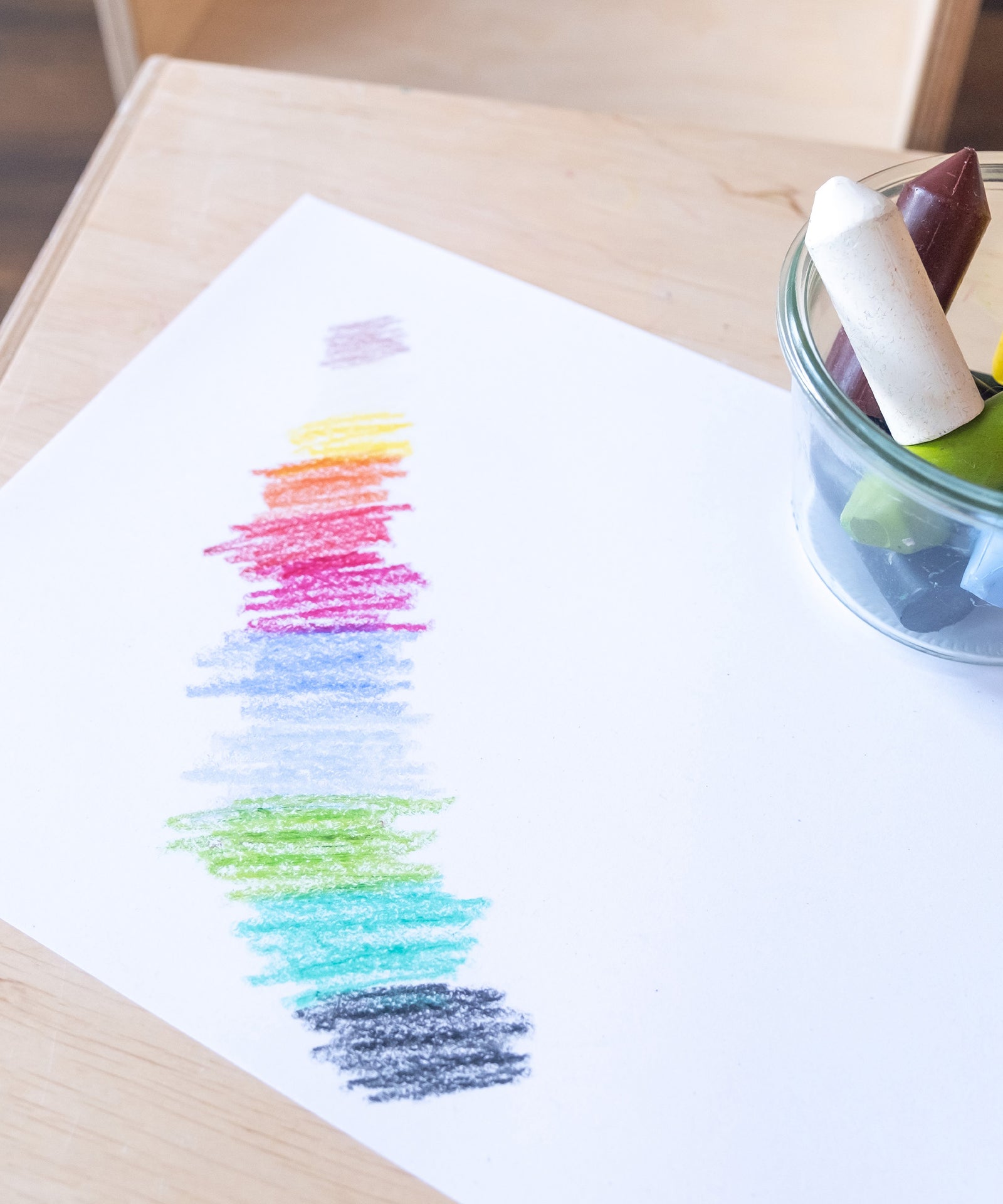 Papier, auf dem nebeneinander in allen Farben der Wachsmalstifte gemalt wurde.