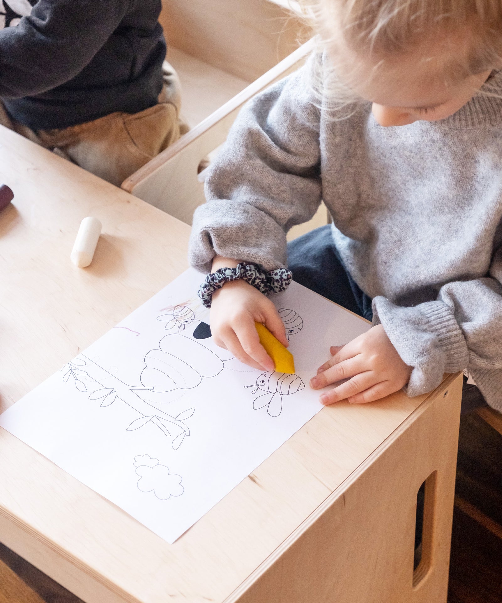 Mädchen malt Ausmalbild mit Wachsmalstiften aus.